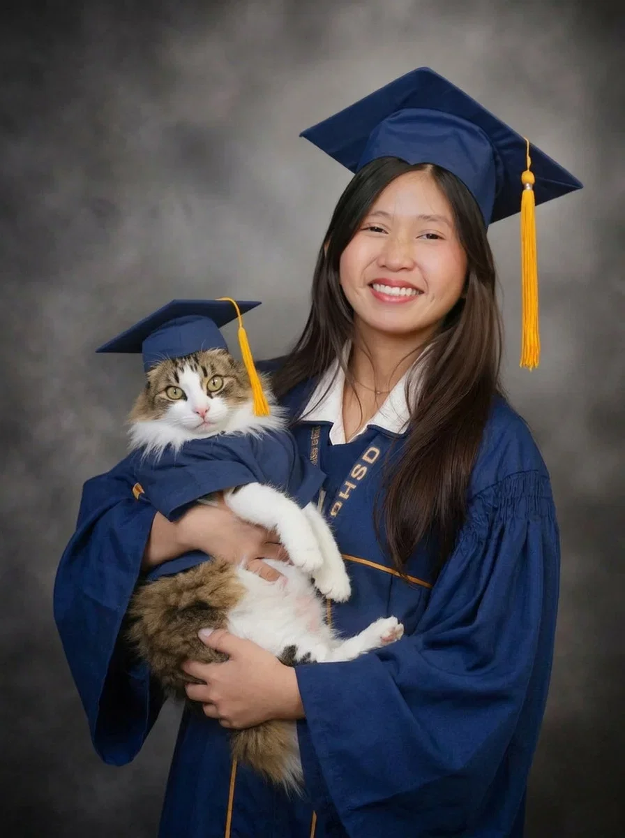 Coco the cat cradled by the graduate